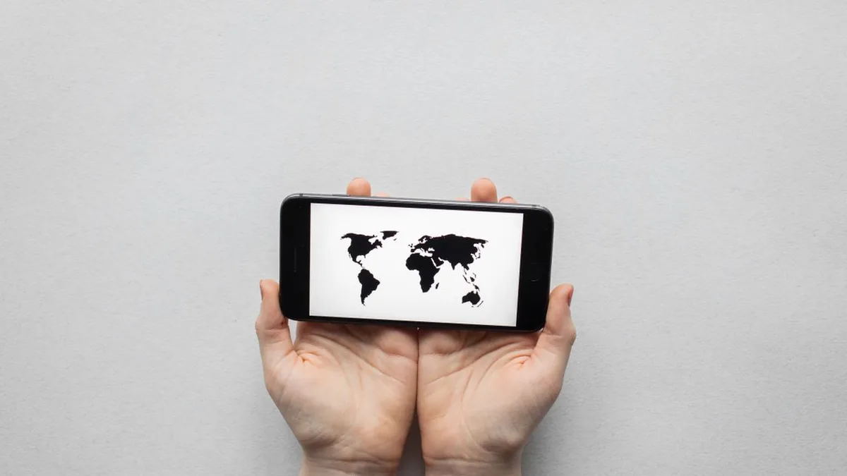 A smartphone beside a world map to represent international phone-number handling (Photo by Monstera Production, Pexels)